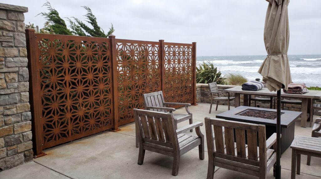 A heavy-duty metal privacy screen securely anchored on a windy patio with patio furniture. A heavy-duty metal privacy screen securely anchored on a windy patio with patio furniture.