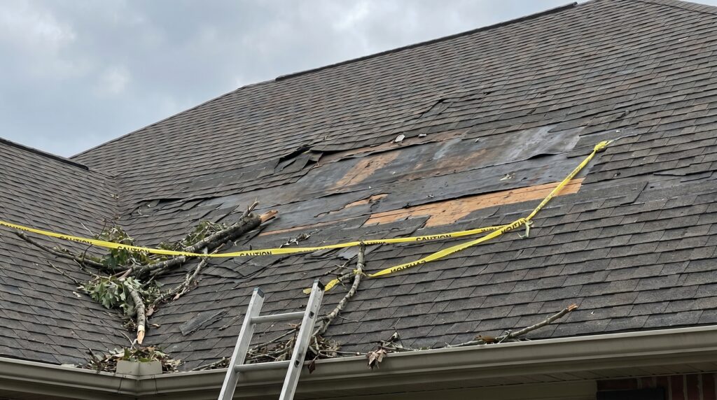 A residential asphalt shingle roof with missing shingles after storm damage, showing exposed underlayment and a potential leak risk that may require repair or full roof replacement. A roof with several missing asphalt shingles after wind damage exposing the underlayment