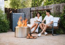 Solo Stove Reviews 2026: Bonfire vs. Yukon vs. Ranger A happy couple sitting on a backyard wood deck at dusk, relaxing in front of a burning, smokeless Solo Stove Bonfire fire pit.