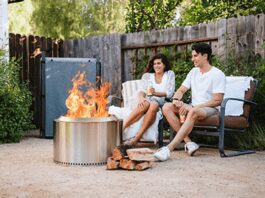 Solo Stove Reviews 2026: Bonfire vs. Yukon vs. Ranger A happy couple sitting on a backyard wood deck at dusk, relaxing in front of a burning, smokeless Solo Stove Bonfire fire pit.