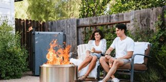 Solo Stove Reviews 2026: Bonfire vs. Yukon vs. Ranger A happy couple sitting on a backyard wood deck at dusk, relaxing in front of a burning, smokeless Solo Stove Bonfire fire pit.