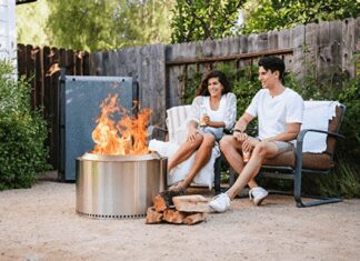 Solo Stove Reviews 2026: Bonfire vs. Yukon vs. Ranger A happy couple sitting on a backyard wood deck at dusk, relaxing in front of a burning, smokeless Solo Stove Bonfire fire pit.