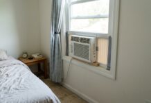 Cheap Window Air Conditioners Under $100 in 2026 Small cheap window air conditioner under $100 installed in a bedroom.