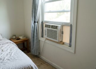 Cheap Window Air Conditioners Under $100 in 2026 Small cheap window air conditioner under $100 installed in a bedroom.