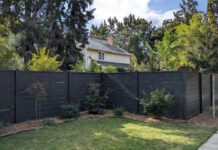 Black Vinyl Fence: Is It Worth the Cost? (Pros & Cons) A sleek, modern black vinyl privacy fence surrounding a beautifully landscaped suburban yar