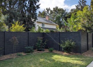 Black Vinyl Fence: Is It Worth the Cost? (Pros & Cons) A sleek, modern black vinyl privacy fence surrounding a beautifully landscaped suburban yar