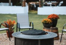 Solo Stove Surround Review 2026: Is The Protective Barrier Worth It? A burning Solo Stove fire pit placed securely inside the Surround protective barrier on a backyard patio at dusk. Two drinks and a bowl of snacks rest safely on the perforated metal tabletop, demonstrating the cool-to-touch safety feature.