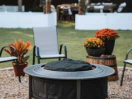 Solo Stove Surround Review 2026: Is The Protective Barrier Worth It? A burning Solo Stove fire pit placed securely inside the Surround protective barrier on a backyard patio at dusk. Two drinks and a bowl of snacks rest safely on the perforated metal tabletop, demonstrating the cool-to-touch safety feature.