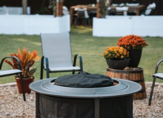 Solo Stove Surround Review 2026: Is The Protective Barrier Worth It? A burning Solo Stove fire pit placed securely inside the Surround protective barrier on a backyard patio at dusk. Two drinks and a bowl of snacks rest safely on the perforated metal tabletop, demonstrating the cool-to-touch safety feature.