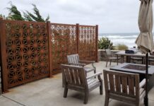 Best Privacy Screens for Windy Areas (2026): Wind-Resistant Options That Actually Work A heavy-duty metal privacy screen securely anchored on a windy patio with patio furniture.