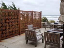 Best Privacy Screens for Windy Areas (2026): Wind-Resistant Options That Actually Work A heavy-duty metal privacy screen securely anchored on a windy patio with patio furniture.