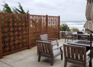 Best Privacy Screens for Windy Areas (2026): Wind-Resistant Options That Actually Work A heavy-duty metal privacy screen securely anchored on a windy patio with patio furniture.