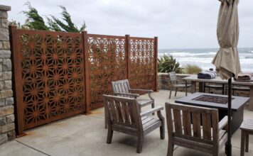 Best Privacy Screens for Windy Areas (2026): Wind-Resistant Options That Actually Work A heavy-duty metal privacy screen securely anchored on a windy patio with patio furniture.