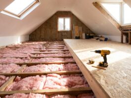 Attic Flooring 2026: Plywood vs OSB, Installation Guide & Exact Costs Installing OSB attic flooring over thick insulation using raised loft legs.