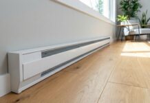 Baseboard Heater Covers 2026: DIY Upgrade A clean, modern white baseboard heater replacement cover installed along a freshly painted wall in a living room, showing the DIY transformation.