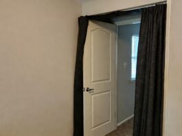 Door Soundproofing Guide 2026: Block Out Noise Fast A homeowner installing an automatic drop door sweep to block noise from entering a bedroom.