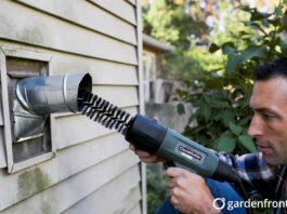 Dryer Vent Cleaning Price 2026: Actual Costs & DIY Tips A homeowner using a rotary brush tool to clean a clogged dryer vent to prevent a house fire.