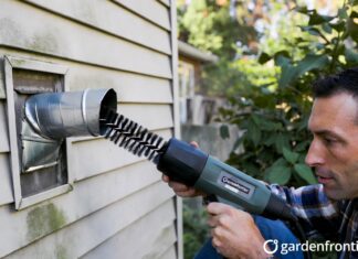 Dryer Vent Cleaning Price 2026: Actual Costs & DIY Tips A homeowner using a rotary brush tool to clean a clogged dryer vent to prevent a house fire.