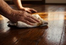 Floorboard Wax Guide: Apply & Remove Wax on Wood Floors (2026) A homeowner buffing rich liquid wax into traditional wooden floorboards to restore their shine.