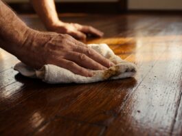 Floorboard Wax Guide: Apply & Remove Wax on Wood Floors (2026) A homeowner buffing rich liquid wax into traditional wooden floorboards to restore their shine.