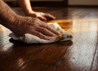 Floorboard Wax Guide: Apply & Remove Wax on Wood Floors (2026) A homeowner buffing rich liquid wax into traditional wooden floorboards to restore their shine.