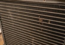 HVAC Evaporator Coil Guide: Cleaning & Replacement (2026) A homeowner inspecting a clean hvac evaporator coil inside their attic air conditioning unit.