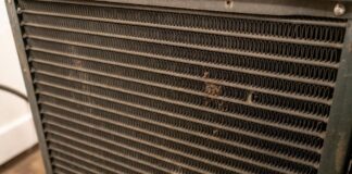 HVAC Evaporator Coil Guide: Cleaning & Replacement (2026) A homeowner inspecting a clean hvac evaporator coil inside their attic air conditioning unit.