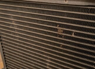 HVAC Evaporator Coil Guide: Cleaning & Replacement (2026) A homeowner inspecting a clean hvac evaporator coil inside their attic air conditioning unit.