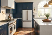 Matte White Appliances with Gold Handles: 2026 Design Guide A luxurious modern kitchen featuring stylish matte white appliances with brushed gold handles, paired with elegant navy blue cabinets and a white quartz countertop.