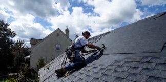 Roof Replacement Cost & Timing (2026): A $22k Mistake A professional roofer installing new architectural asphalt shingles on a residential home.