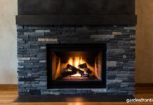 Soapstone Fireplaces (2026): Surrounds, Inserts & Maintenance A beautifully oiled dark soapstone fireplace surround radiating heat in a cozy living room