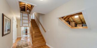 Best Attic Doors: Access Panels, Pull-Down Stairs & Insulated Options A white attic access door in a hallway ceiling with pull-down attic stairs partially opened