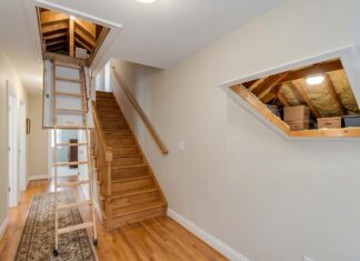 Best Attic Doors: Access Panels, Pull-Down Stairs & Insulated Options A white attic access door in a hallway ceiling with pull-down attic stairs partially opened