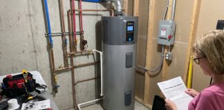 Heat Pump Water Heater Cost: Unit Price, Installation, Rebates & Hidden Expenses A hybrid heat pump water heater installed in a utility room with plumbing and electrical connections