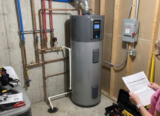 Heat Pump Water Heater Cost: Unit Price, Installation, Rebates & Hidden Expenses A hybrid heat pump water heater installed in a utility room with plumbing and electrical connections