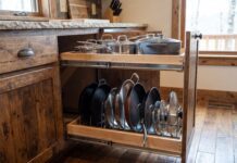 Best Pull Out Pot and Pan Holders for Kitchen Cabinets Pull out pot and pan holder installed inside a lower kitchen cabinet with cookware, lids, and frying pans organized on sliding shelves