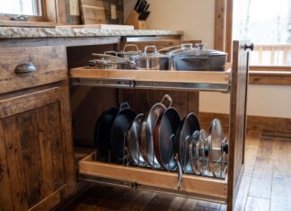 Best Pull Out Pot and Pan Holders for Kitchen Cabinets Pull out pot and pan holder installed inside a lower kitchen cabinet with cookware, lids, and frying pans organized on sliding shelves