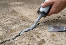 Best Sealer for Concrete Cracks: Driveways, Patios, Floors & Walls A homeowner applying concrete crack sealer into a driveway crack with a caulking gun
