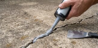 Best Sealer for Concrete Cracks: Driveways, Patios, Floors & Walls A homeowner applying concrete crack sealer into a driveway crack with a caulking gun