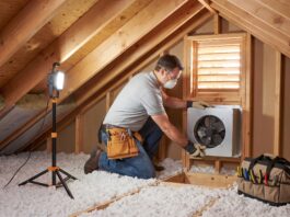 Attic Fan Installation: Cost, Types, Pros, Cons & When It’s Worth It Contractor installing an attic fan near a roof vent in a residential attic