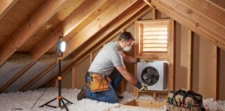 Attic Fan Installation: Cost, Types, Pros, Cons & When It’s Worth It Contractor installing an attic fan near a roof vent in a residential attic