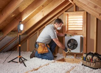 Attic Fan Installation: Cost, Types, Pros, Cons & When It’s Worth It Contractor installing an attic fan near a roof vent in a residential attic