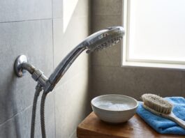 How to Clean a Shower Head and Restore Water Pressure Fast Cleaning a chrome shower head with mineral buildup in a modern bathroom